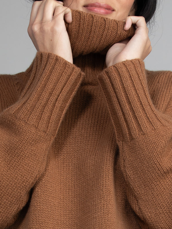 Woman wearing brown turtleneck sweater.