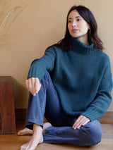 Woman wearing blue turtleneck sweater.