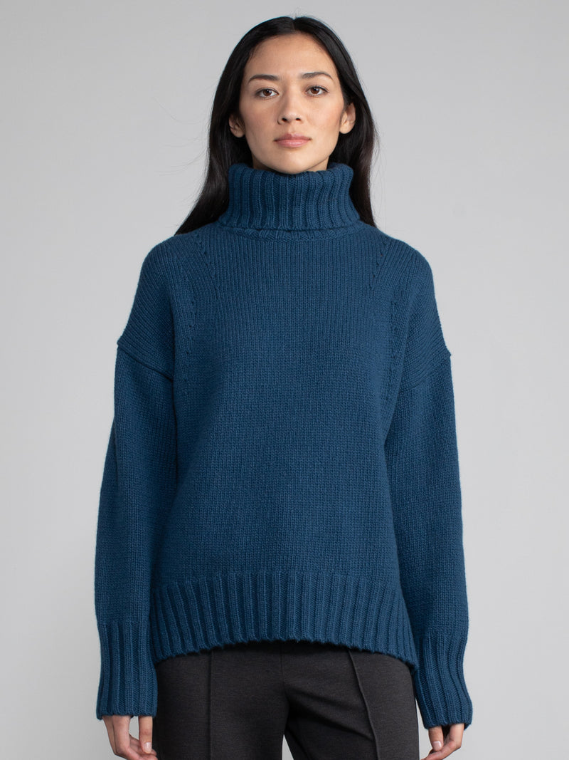 Woman wearing blue turtleneck sweater.