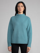 Woman wearing a teal cashmere sweater.