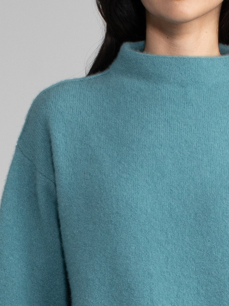 Woman wearing a teal cashmere sweater.