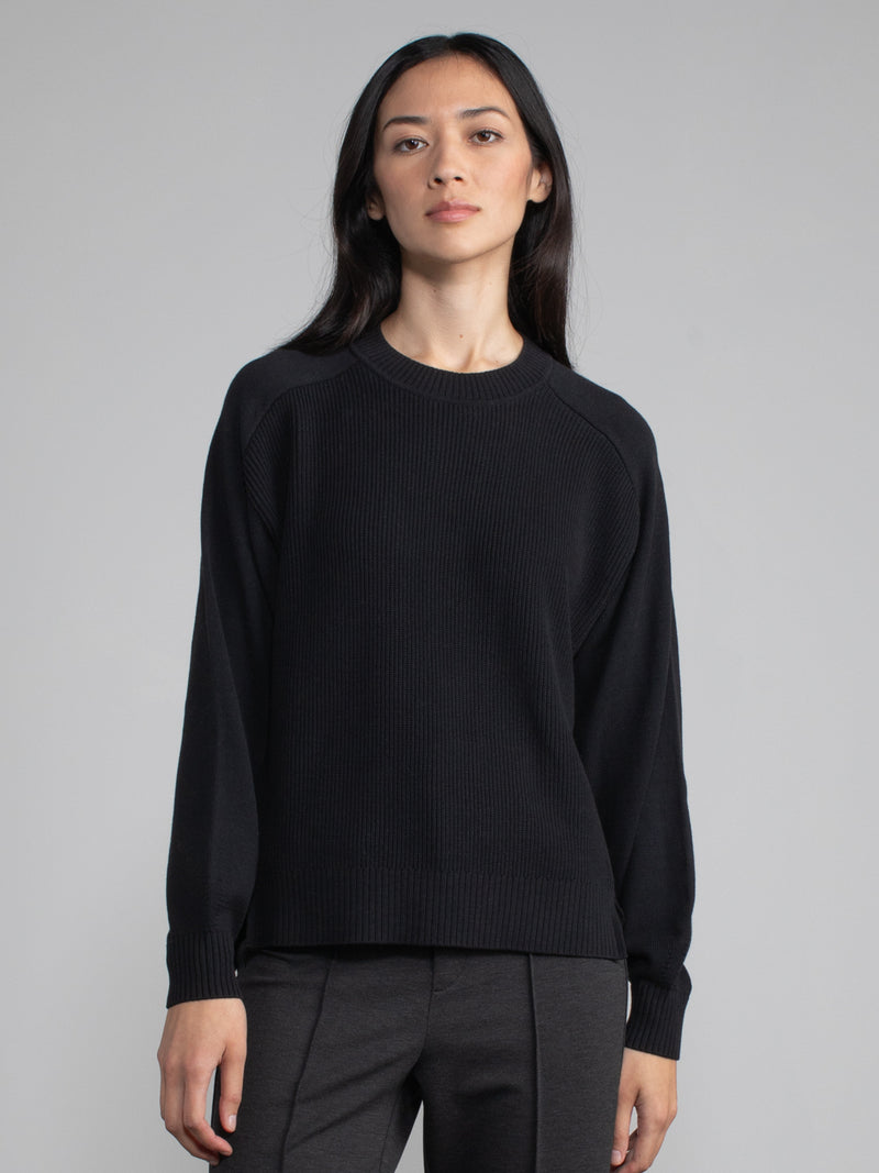 Woman wearing a black ribbed knit sweater.