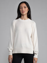 Woman wearing a white ribbed knit sweater.