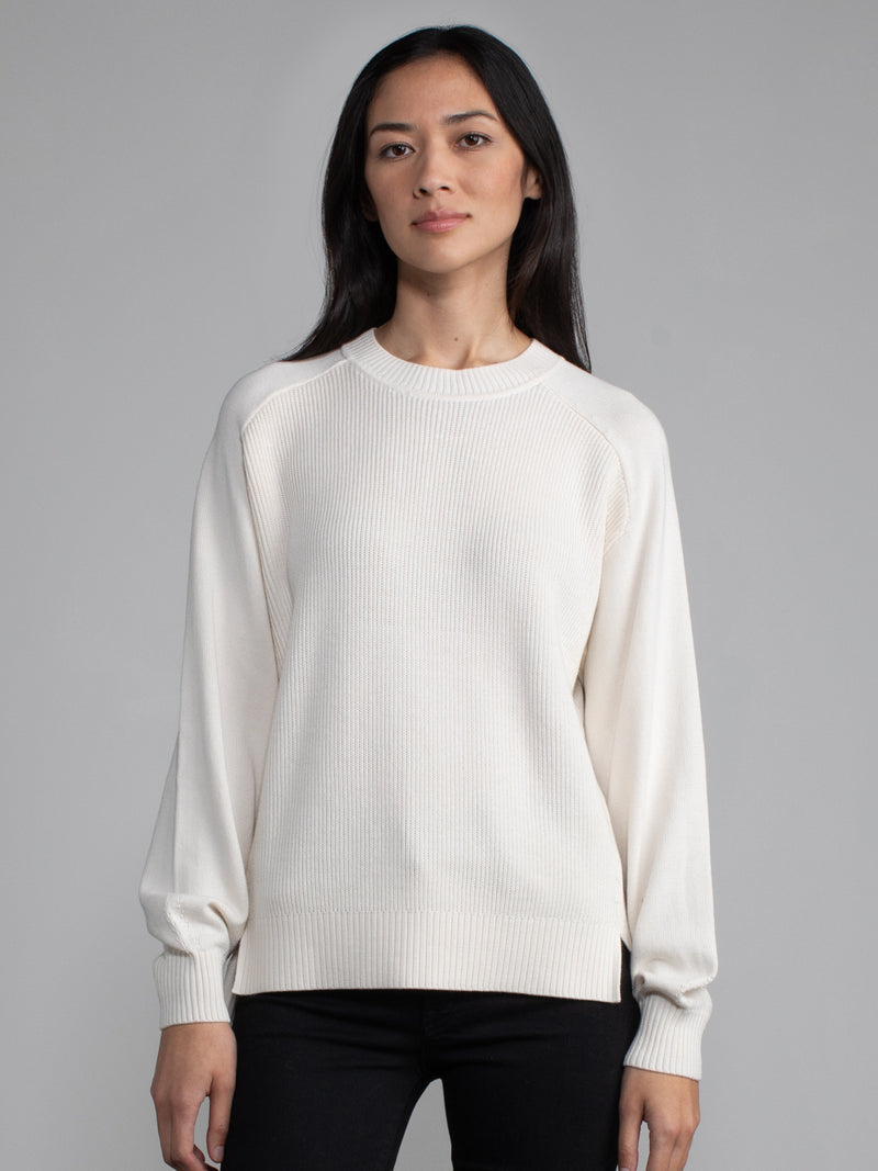 Woman wearing a white ribbed knit sweater.