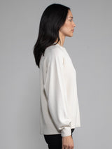 Woman wearing a white ribbed knit sweater.