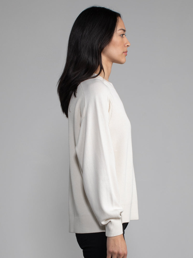 Woman wearing a white ribbed knit sweater.