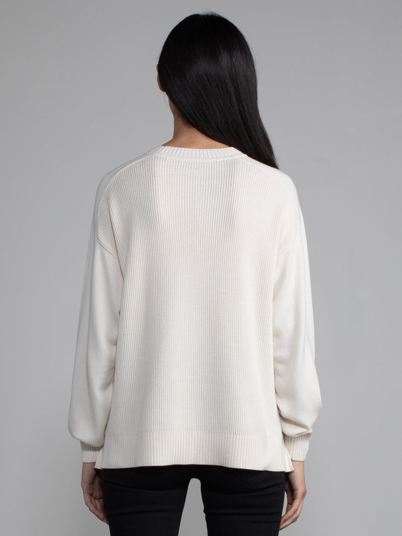 Woman wearing a white ribbed knit sweater.