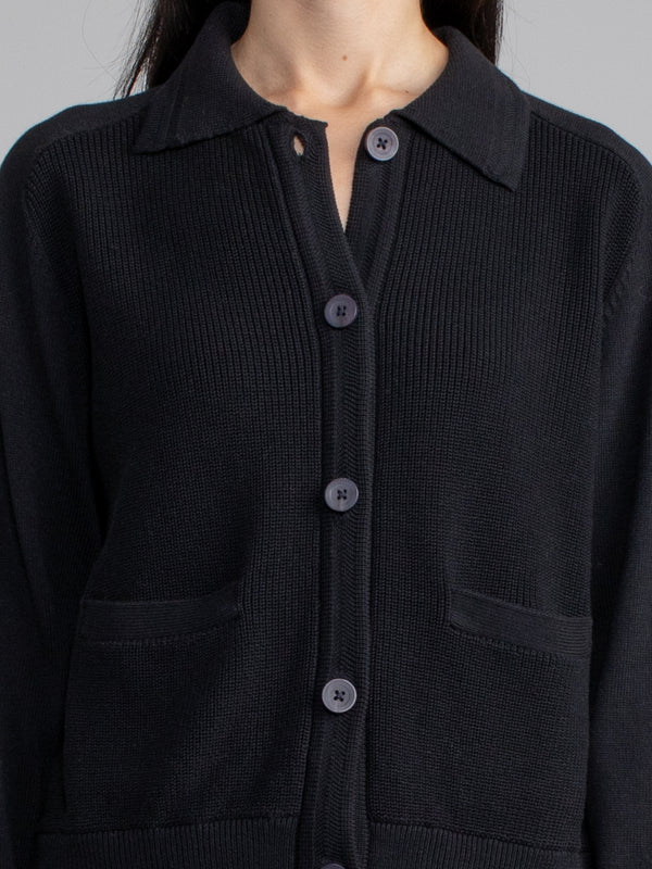 Woman wearing a black polo cardigan sweater.