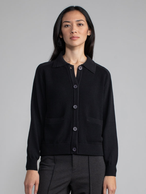 Woman wearing a black polo cardigan sweater.