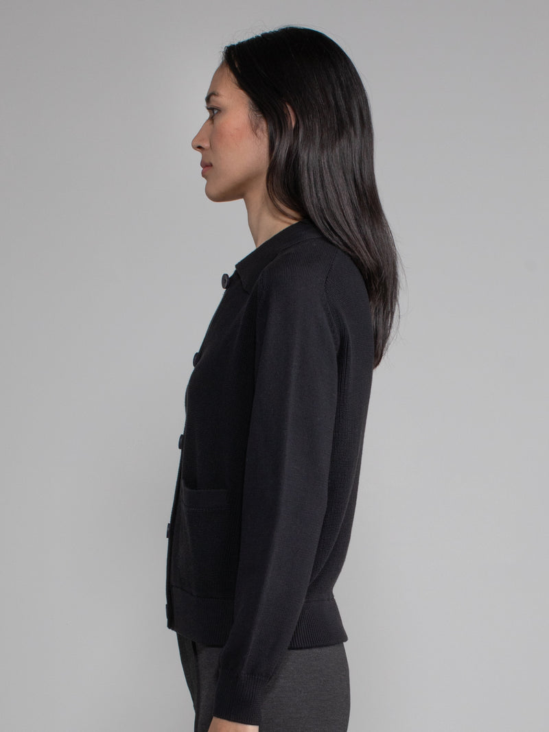 Woman wearing a black polo cardigan sweater.