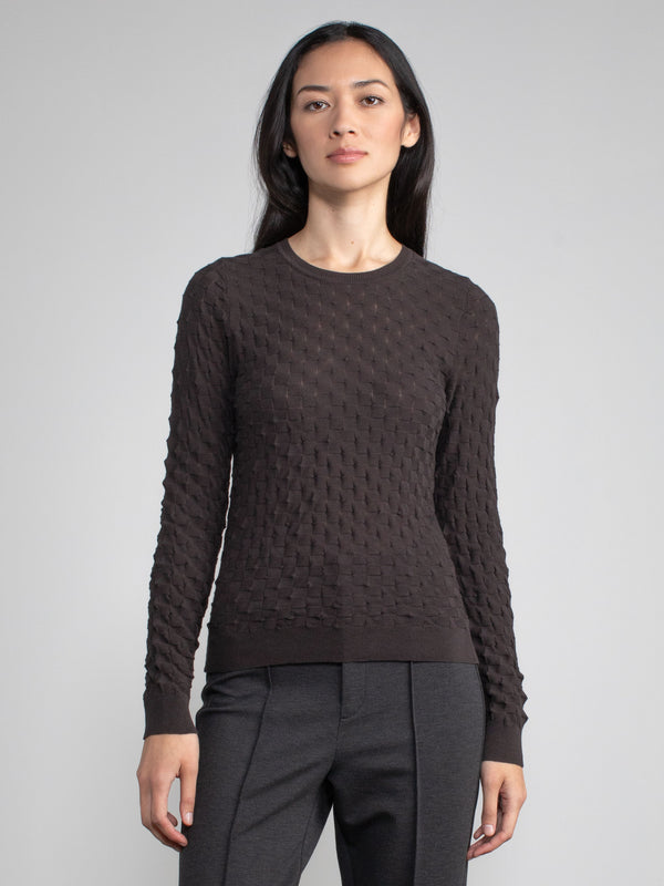 Model wearing the chocolate checkerboard crew and a pair of pants.