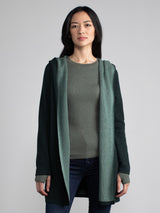 Woman in a light and dark green, long line hooded cardigan.