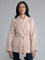 Female model wearing a light pink hooded jacket with a belt.