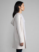 Woman in a white and grey, long line hooded cardigan.