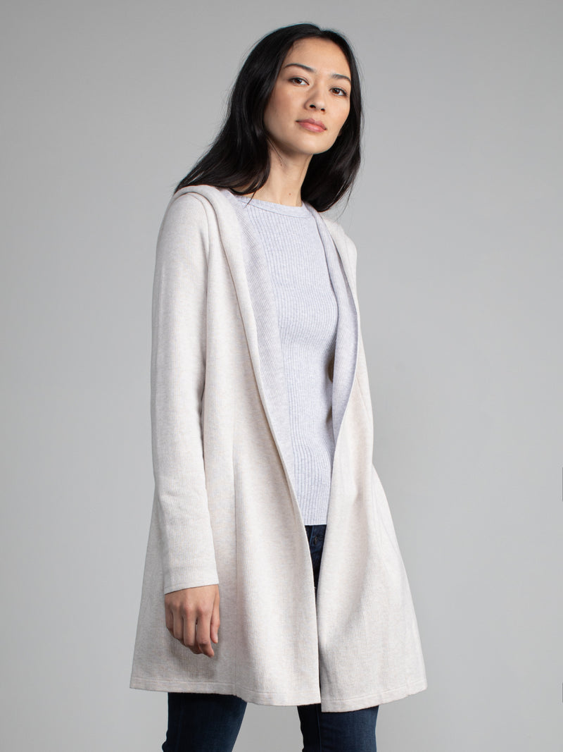 Woman in a white and grey, long line hooded cardigan.
