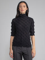 Model wearing the black elbow tneck and a pair of pants.