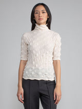 Model wearing the eggshell elbow tneck and a pair of pants.