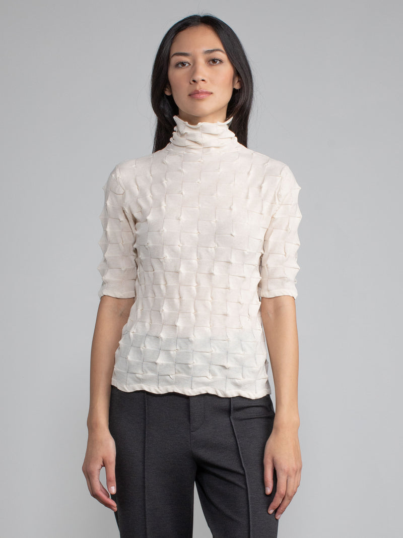 Model wearing the eggshell elbow tneck and a pair of pants.