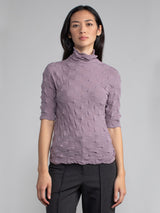 Model wearing the purple elbow tneck and a pair of pants.