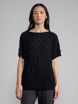 Model wearing the pullover in black and a pair of grey pants.