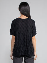 Back view of the model wearing the pullover in black and a pair of grey pants.