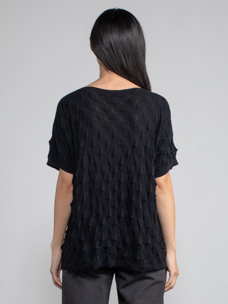 Back view of the model wearing the pullover in black and a pair of grey pants.