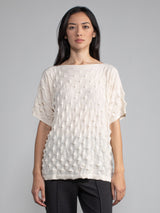 Model wearing the pullover in eggshell color and a pair of grey pants.