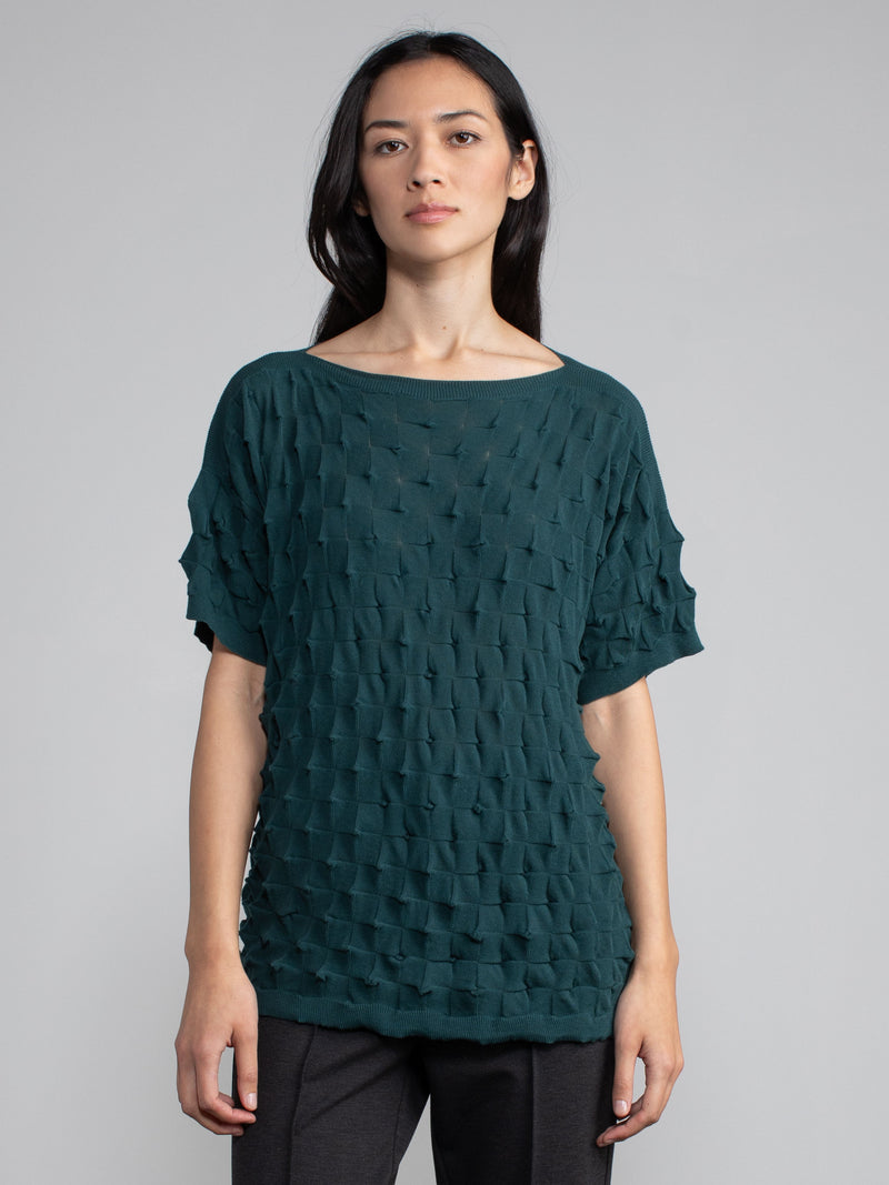 Model wearing the pullover in green and a pair of grey pants.