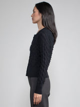 Side view of the model wearing a black cardigan with button closure.