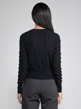 Back view of the model wearing a black cardigan with button closure.