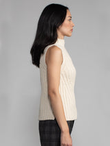 Woman wearing a white sleeveless turtleneck sweater.