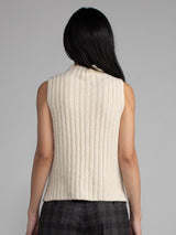 Woman wearing a white sleeveless turtleneck sweater.