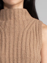 Woman wearing a brown sleeveless turtleneck sweater.
