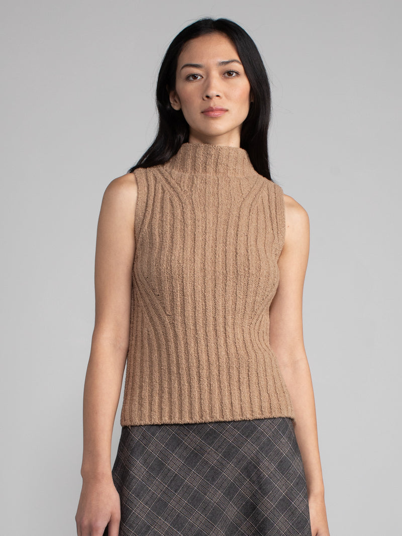 Woman wearing a white sleeveless turtleneck sweater.