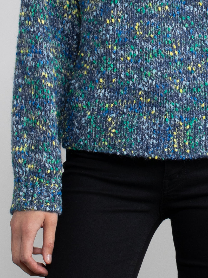 Woman wearing a blue speckled knit sweater.