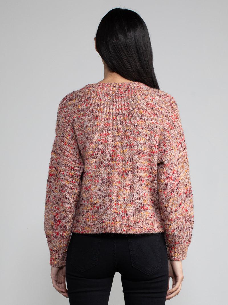 Woman wearing a red speckled knit sweater.