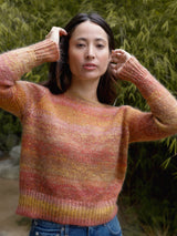 Woman wearing an orange and red knit sweater.