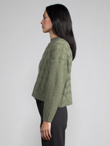 Woman wearing a cropped green cable knit sweater.