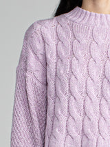 Woman wearing a cropped purple cable knit sweater.