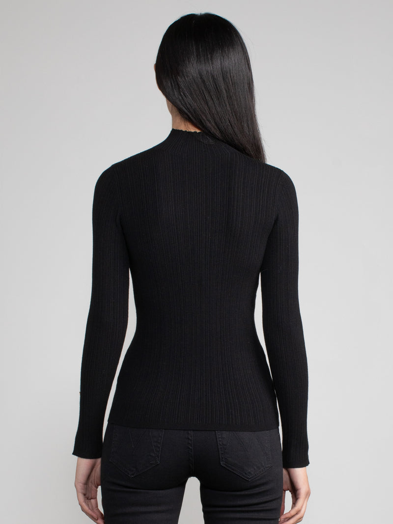 Woman wearing a fitted black turtleneck.