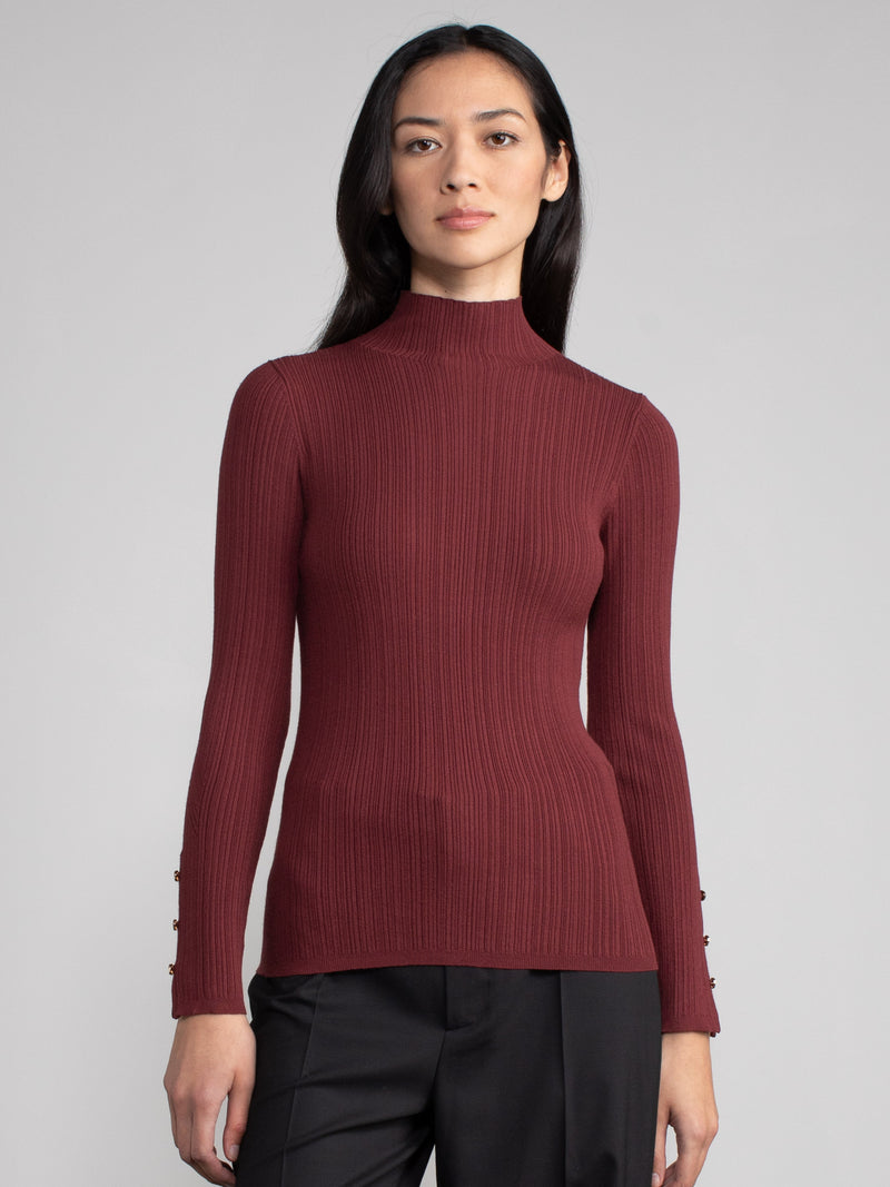 Woman wearing a fitted maroon turtleneck.