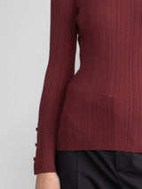Woman wearing a fitted maroon turtleneck.