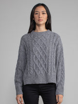 Woman wearing a grey cable knit sweater.