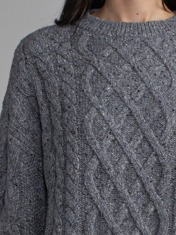Woman wearing a grey cable knit sweater.