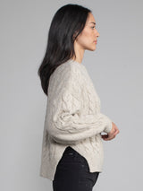 Woman wearing a grey cable knit sweater.
