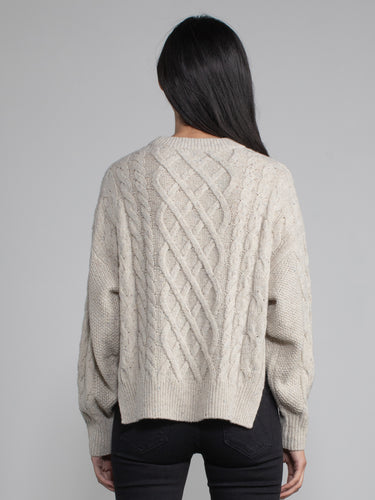 Woman wearing a grey cable knit sweater.