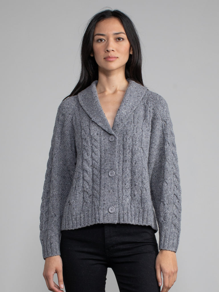 Woman wearing a grey cable knit cardigan.