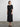 Woman wearing a black dress standing against a plain background