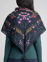Woman wearing a floral scarf around her as a shawl.