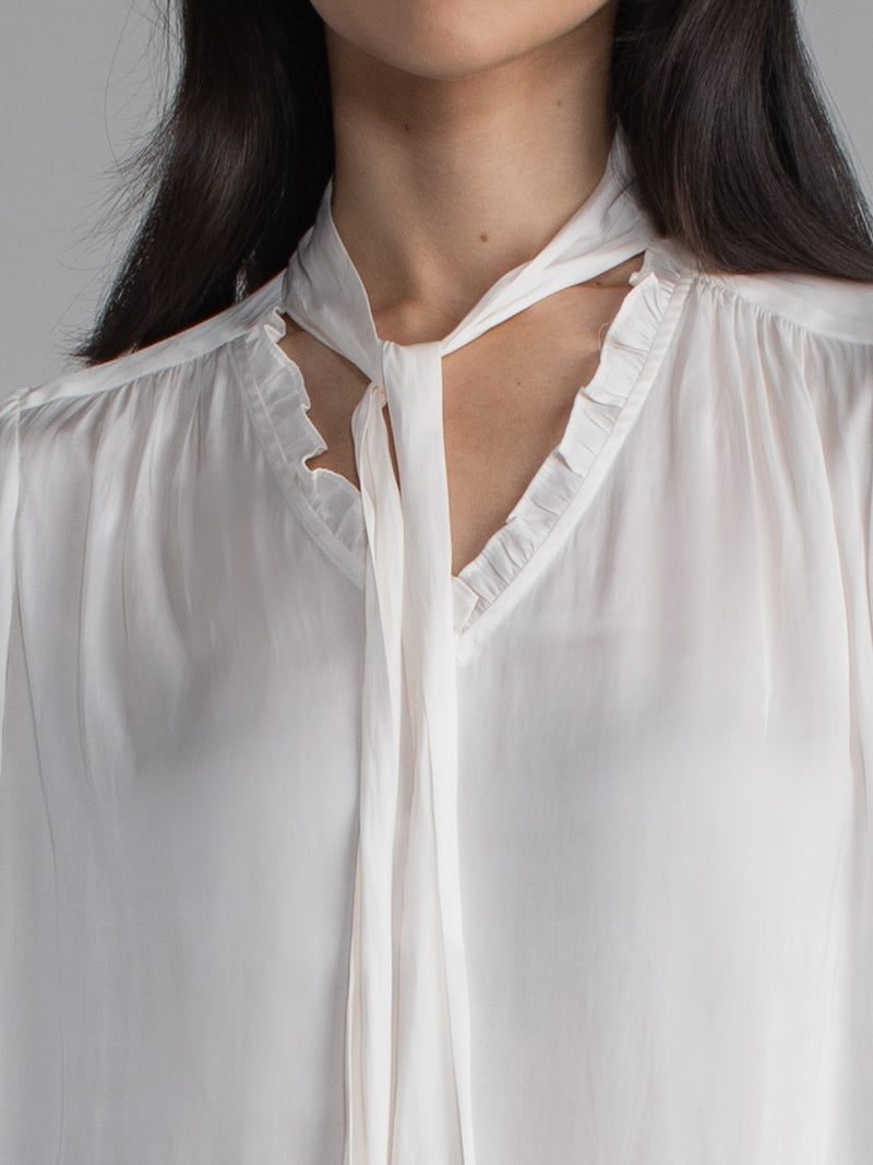 Female wearing white blouse with tie neck